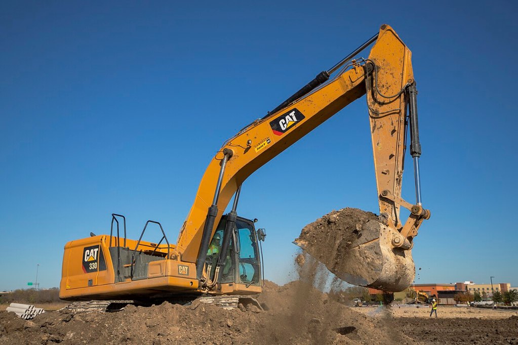 Caterpillar 330 excavator scooping dirt at a construction site