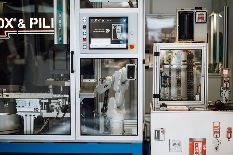 Industrial robotic arm operating machinery inside a factory automation cell