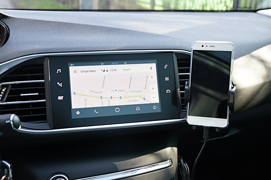 Android Auto running on a car infotainment display next to a connected smartphone
