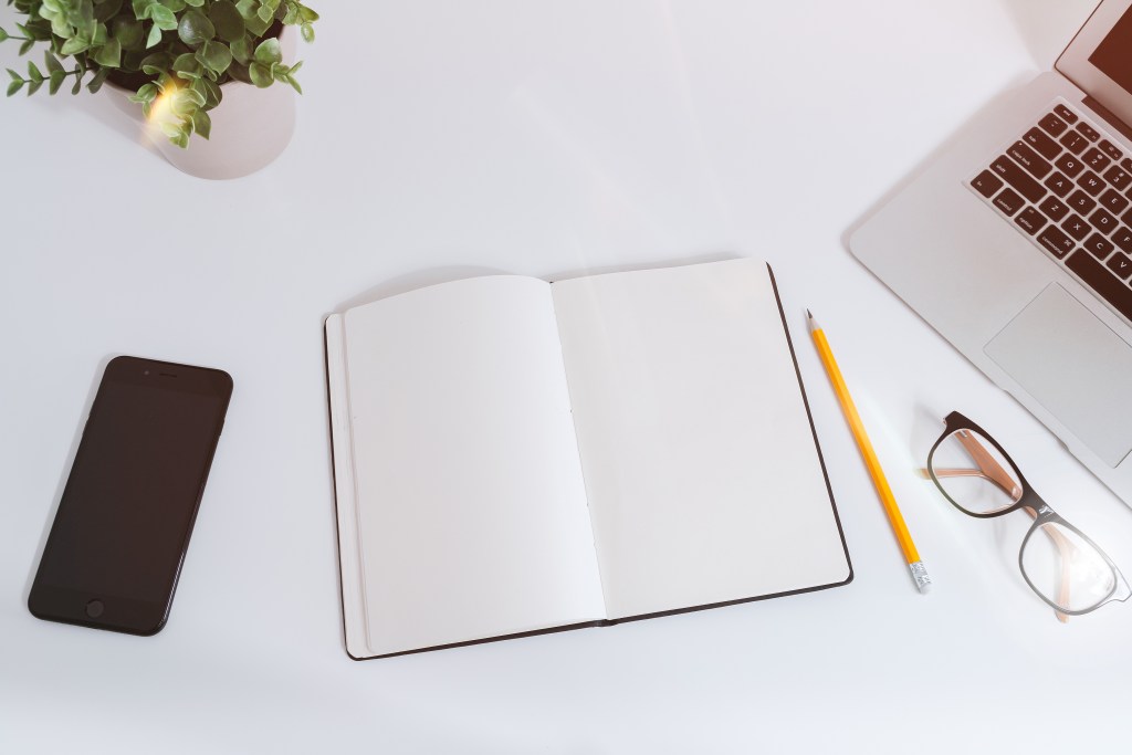 Laptop, smartphone and notebook on a white desk